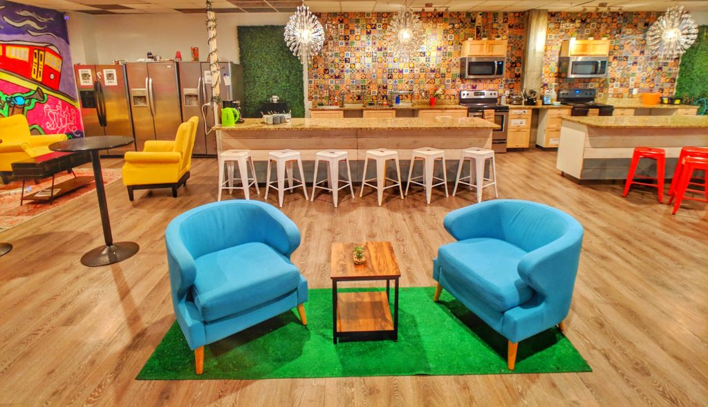 blue chair sitting area with kitchen in background at City House Hostel