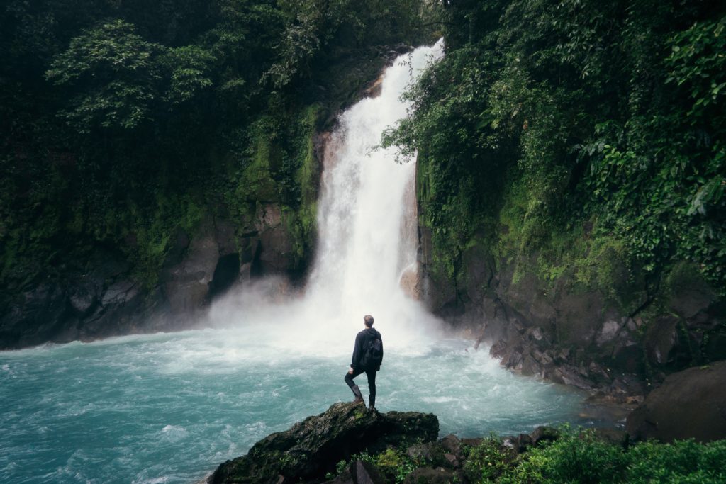 Man standing in front of a large waterfall