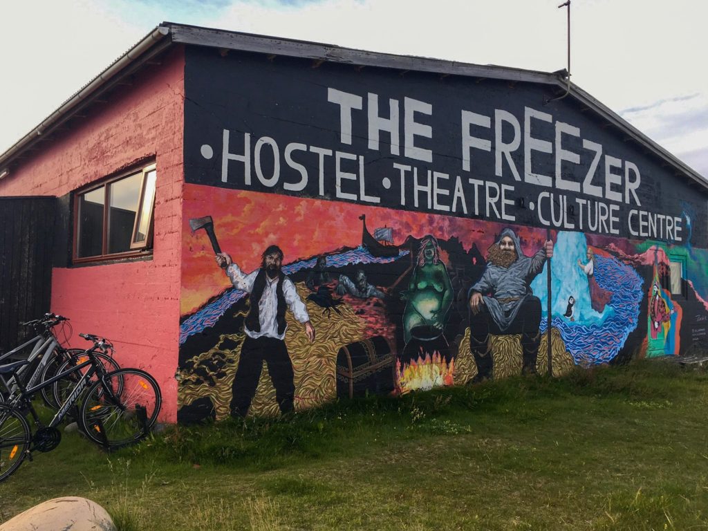 The outside of The Freezer Hostel building. Painted mural featuring people, alien, and scenery.