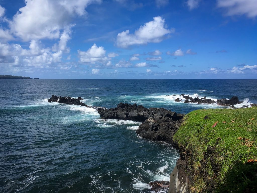 Hawaiian coastline with black rocks into the Pacific Ocean.